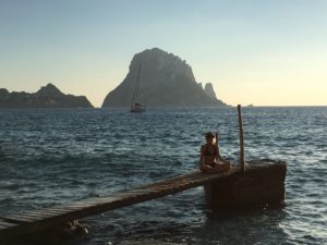 Elke im Meditationssitz auf einem Steg, im Hintergrund der Fels Es Vedra