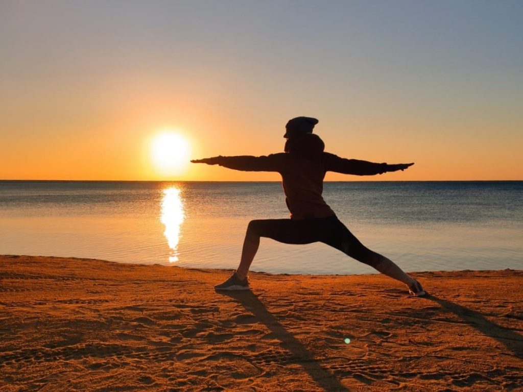 Elke in der Krieger Position bei Sonnenaufgang am Strand in Soma Bay