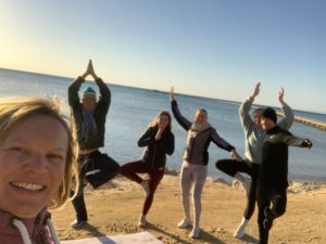 Eine Gruppe Yogis in Bäumchenpose nach der Stunde am Strand