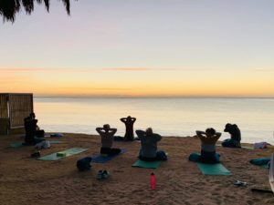 Eine Gruppe Yogis bei Sonnenaufgang am Strand